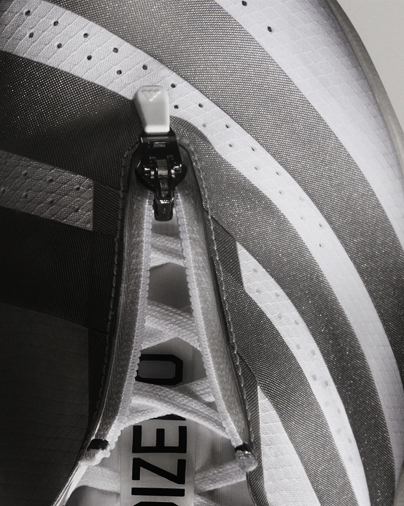 Close-up of a white and gray sneaker with a zipper integrated into the lacing system.