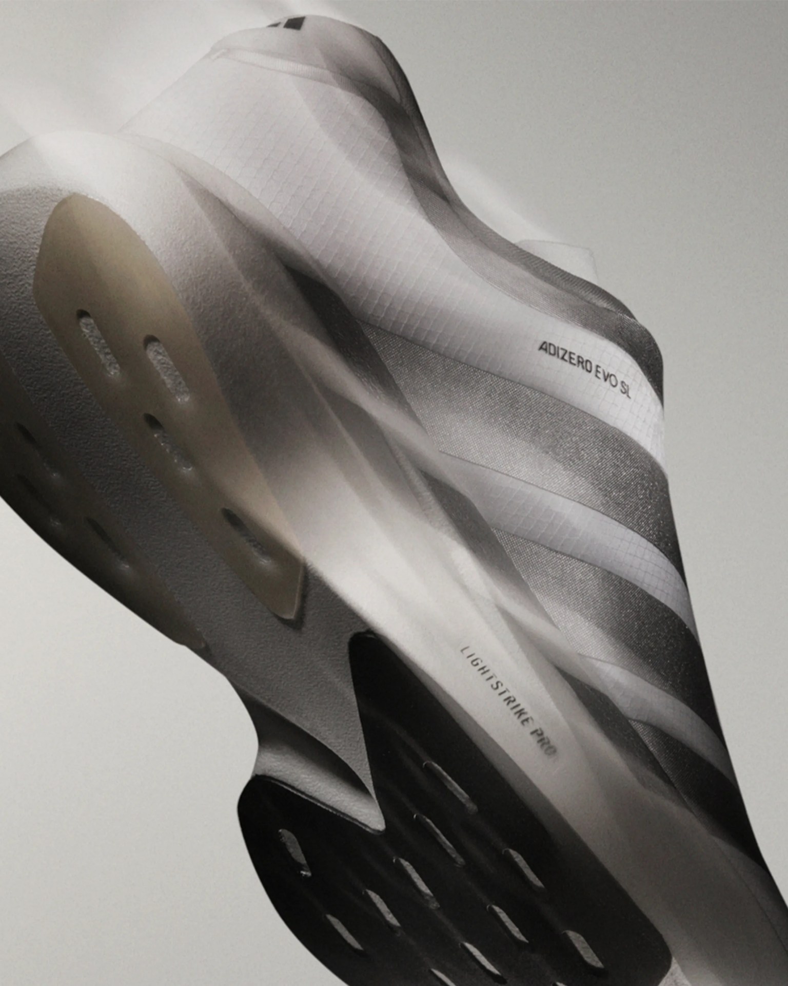 White and gray Adidas Adizero Evo SL running shoe with Lightstrike Pro sole, shown from a low angle.
