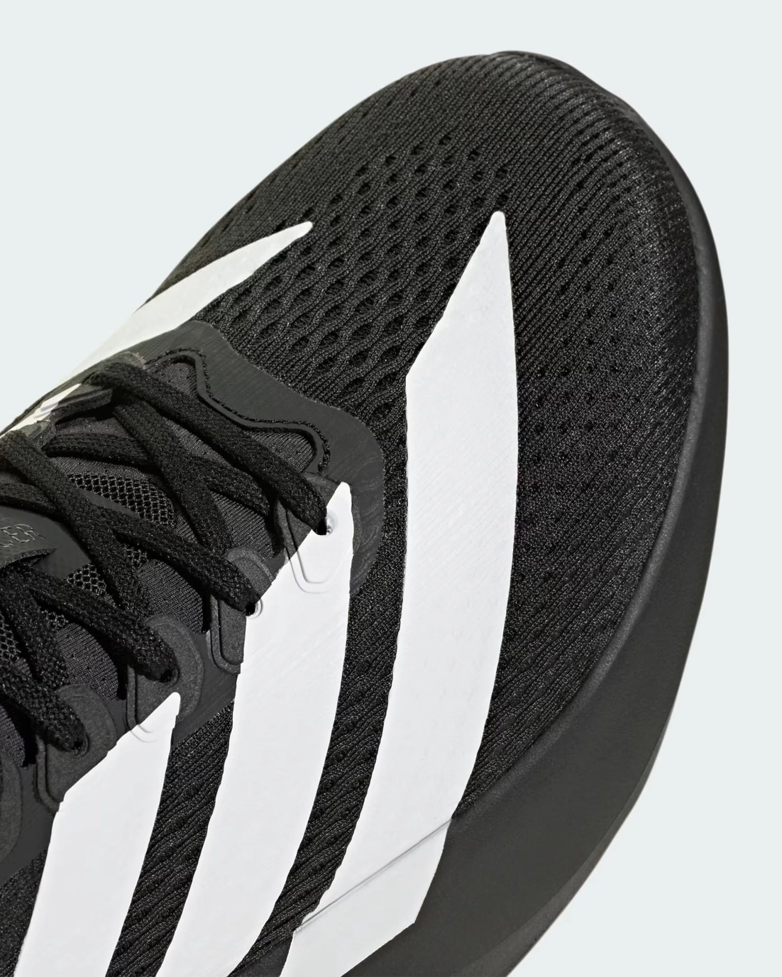 Close-up of black athletic shoe with white stripes and black laces.
