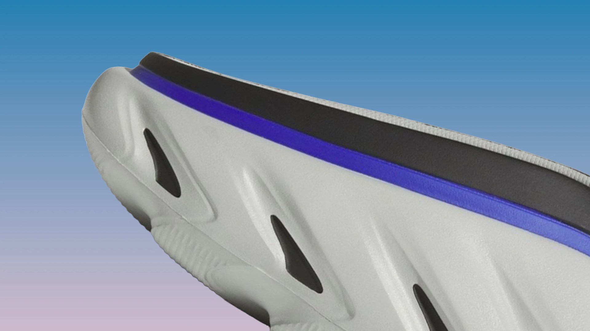 Close-up of a white sneaker sole with black accents and a purple stripe near the black midsole.