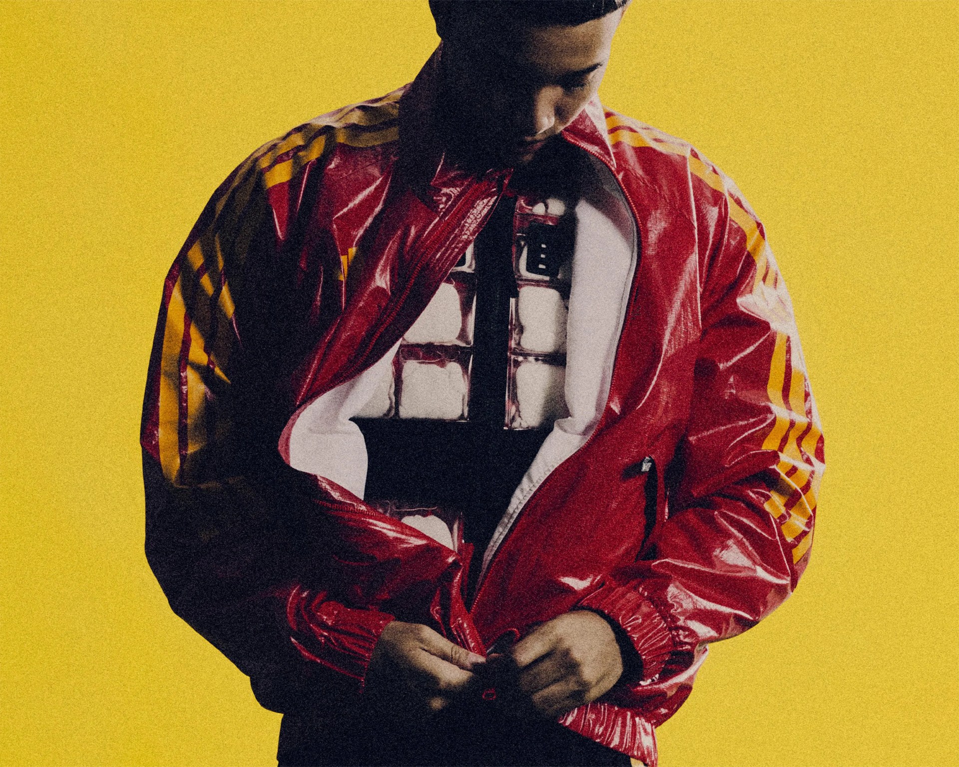 Person wearing a shiny red and yellow jacket over a white shirt with a black design, against a yellow background.