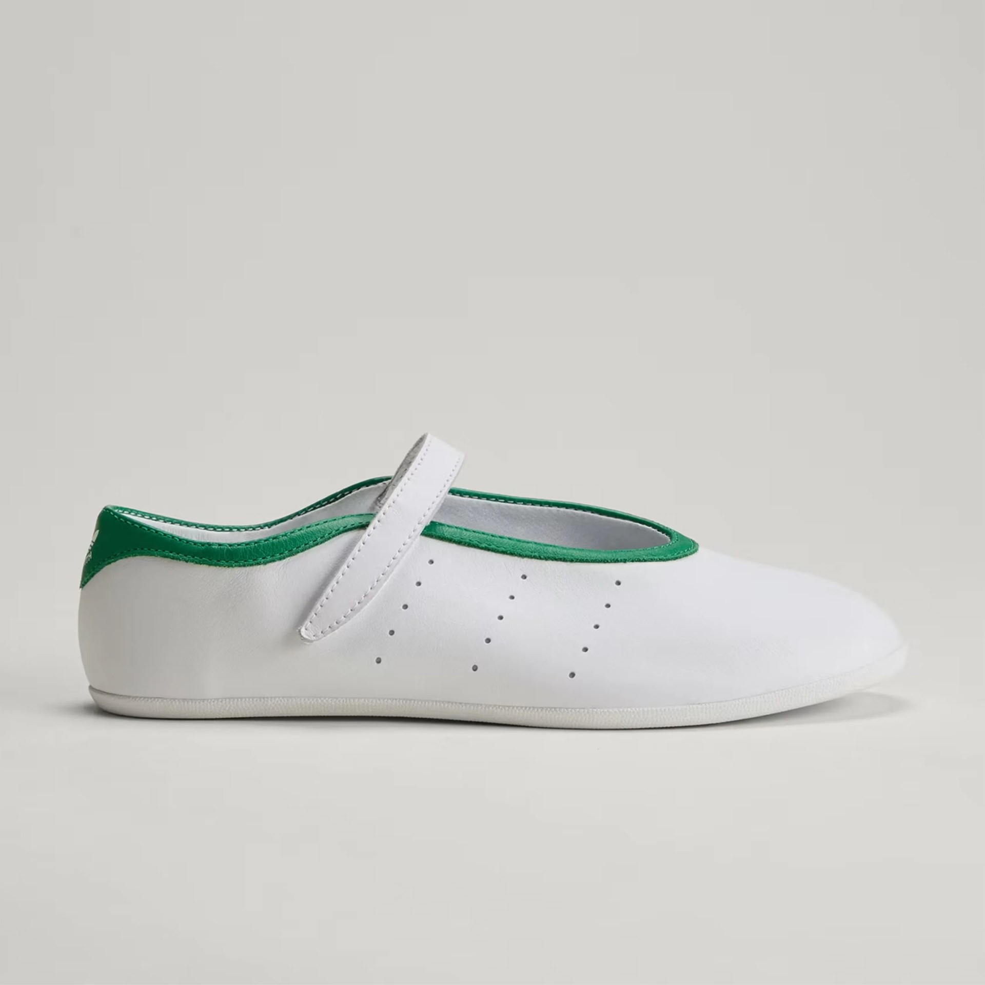 White leather Mary Jane shoe with green trim and perforated side details on a neutral background.