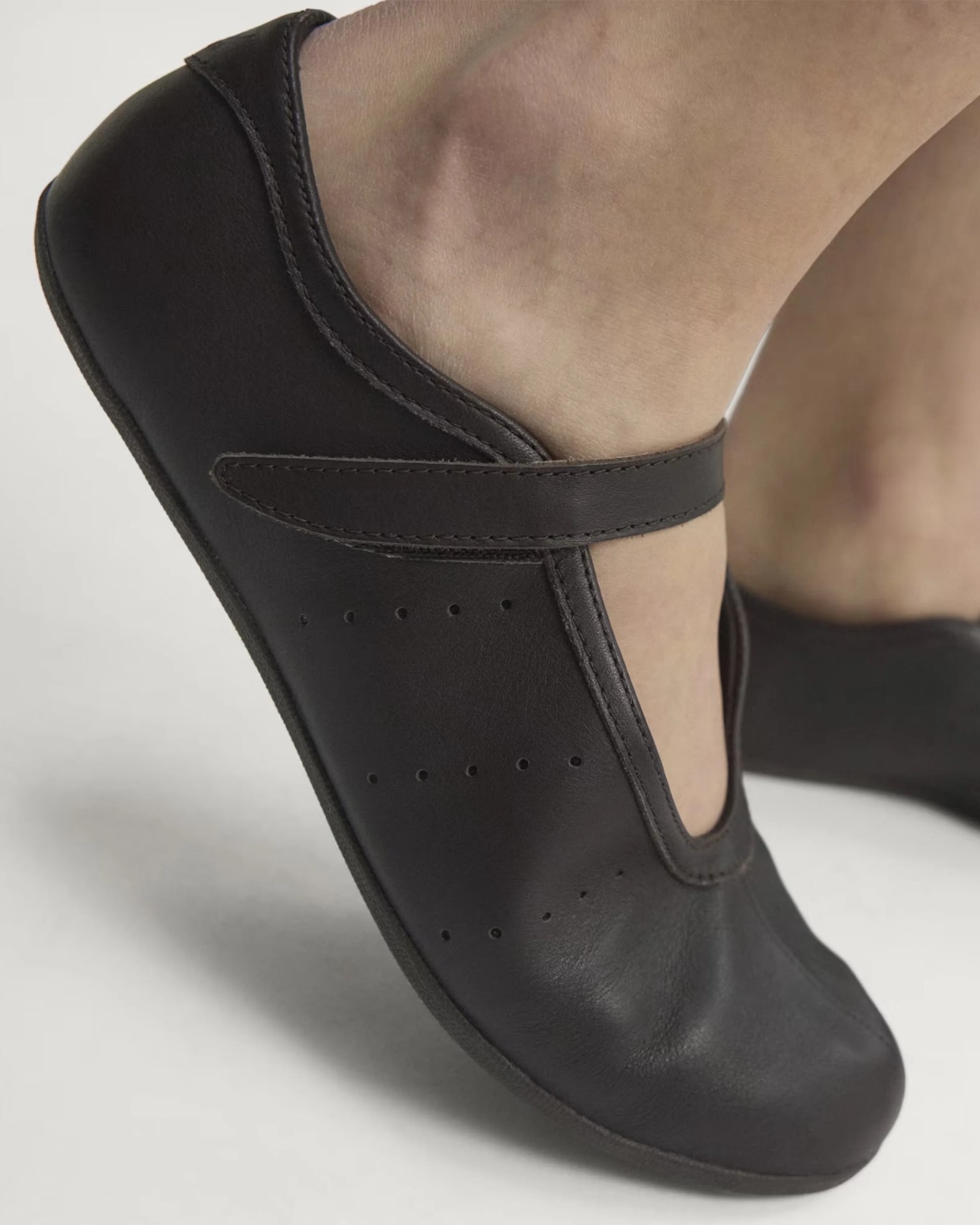 Black leather Mary Jane shoe with a strap across the instep worn on a foot.