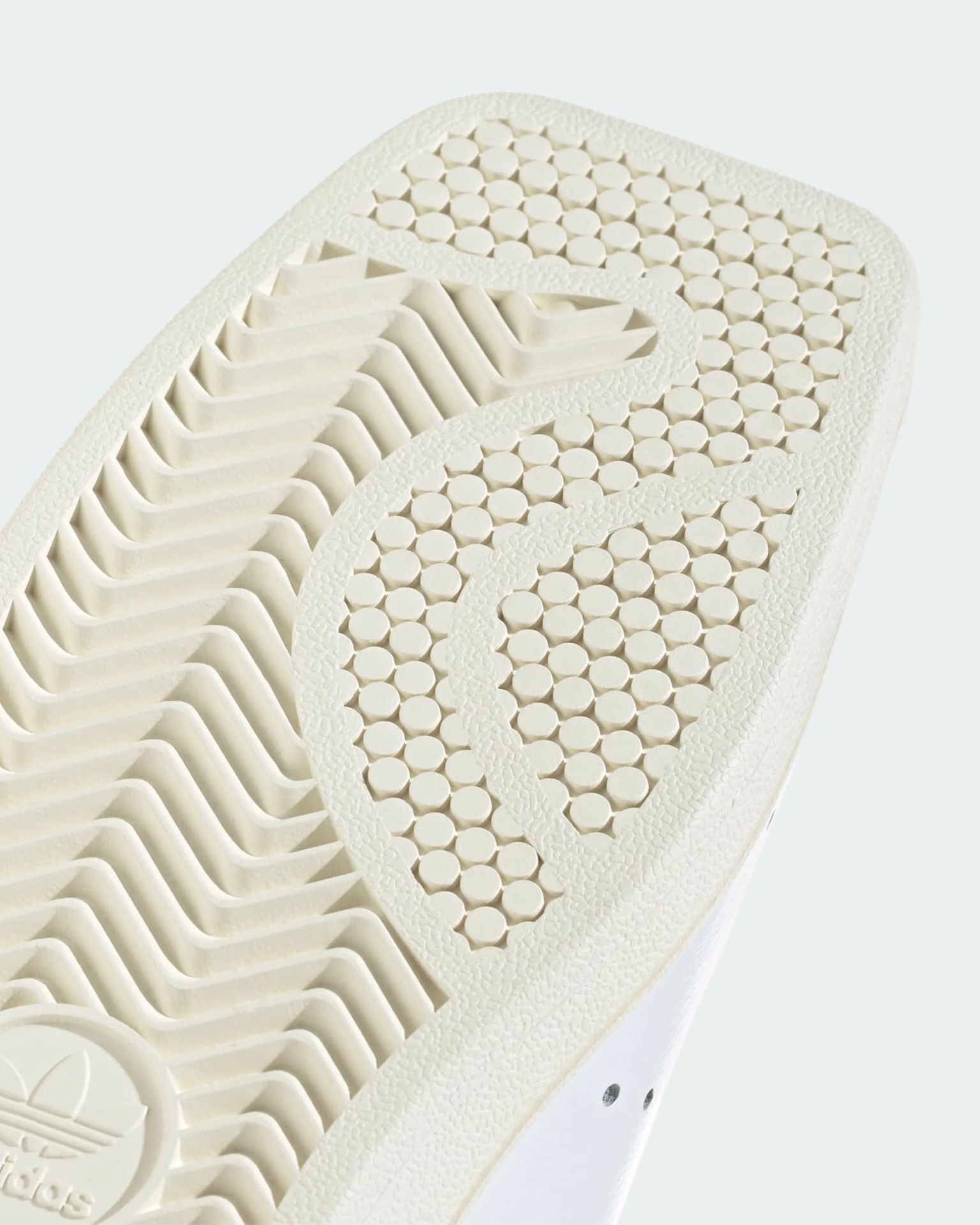 Close-up of a white Adidas shoe sole with circular and zigzag tread patterns.
