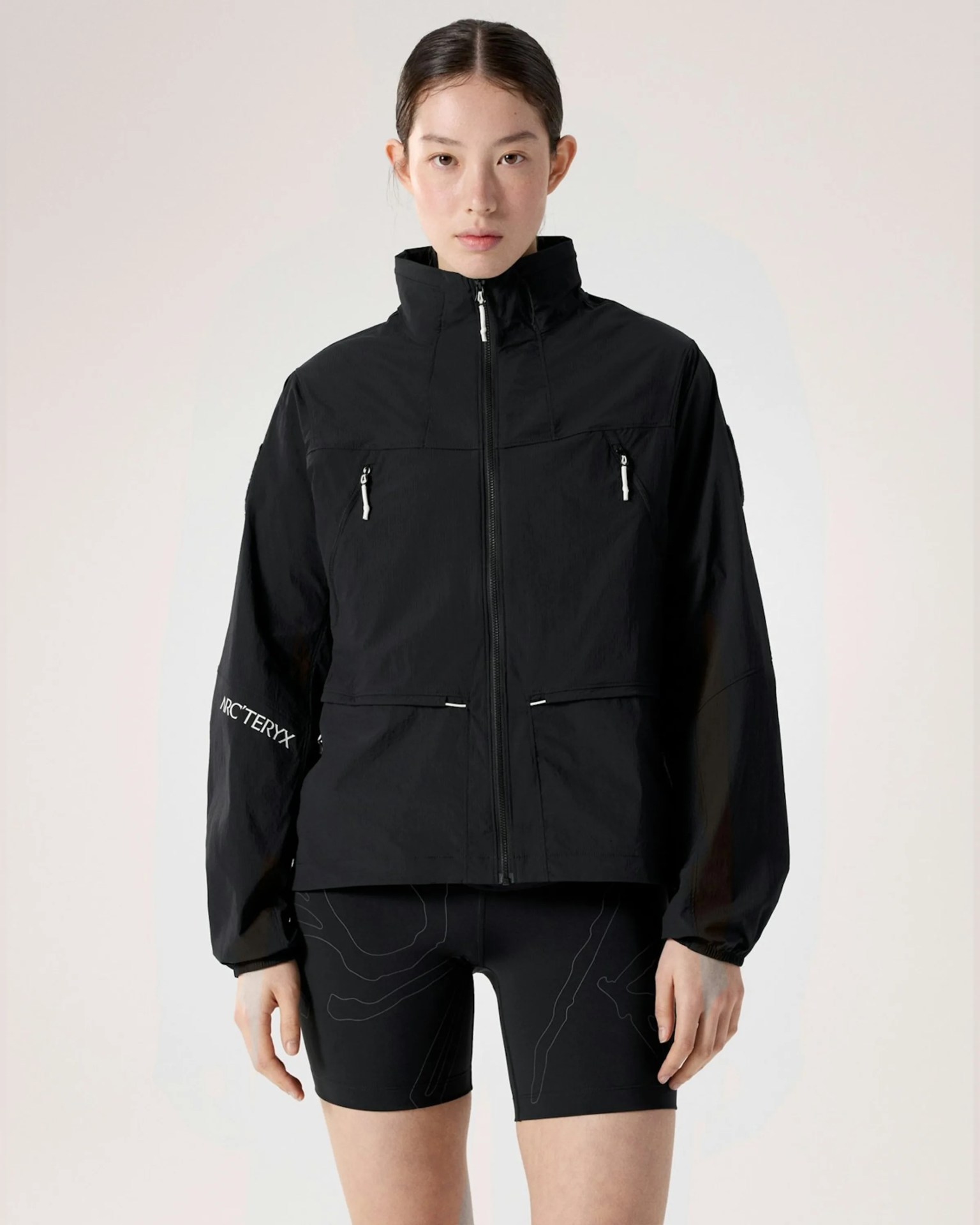 Black zip-up jacket with high collar and zippered chest pockets worn by a person.