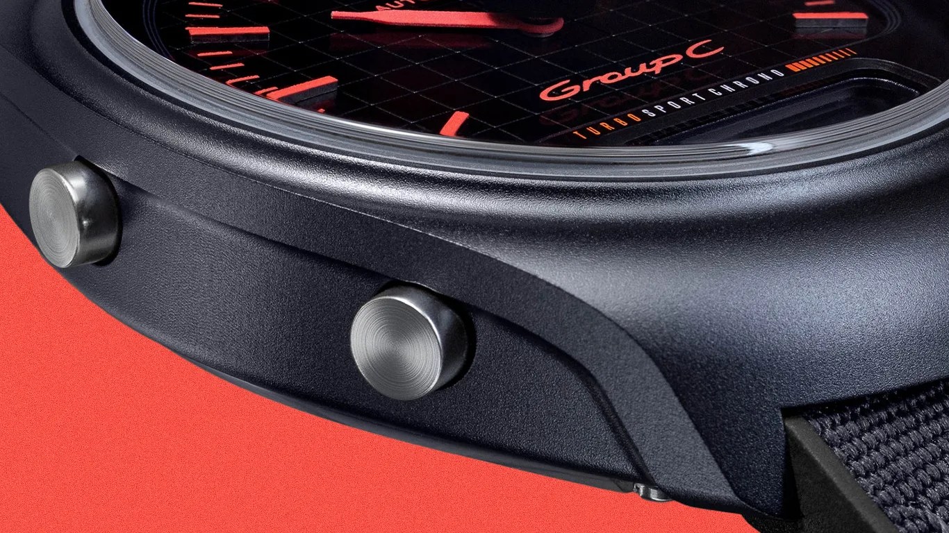 Close-up of a black watch case with two brushed metal pushers and a black dial showing "Group C" and "Turbo Sport Chrono" text.