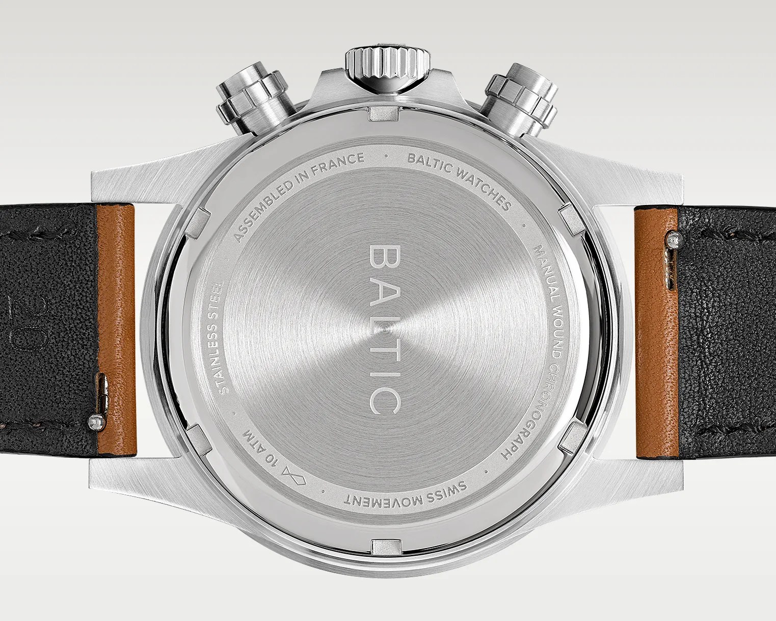 Brushed stainless steel watch back with engraved text and black and brown leather straps attached.