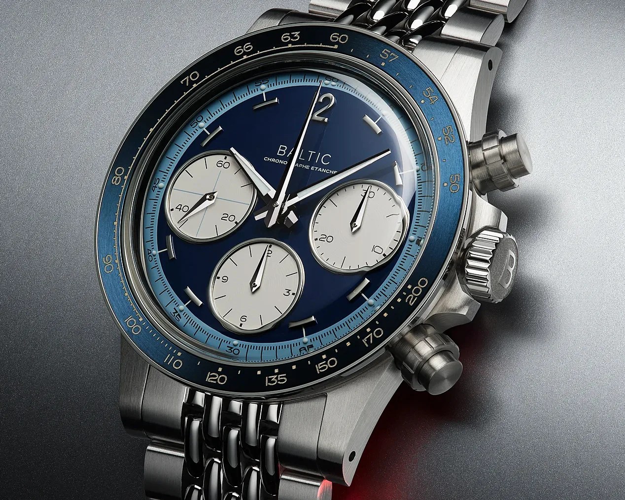 Close-up of a Baltic chronograph watch with a blue dial, three white subdials, and a stainless steel bracelet.
