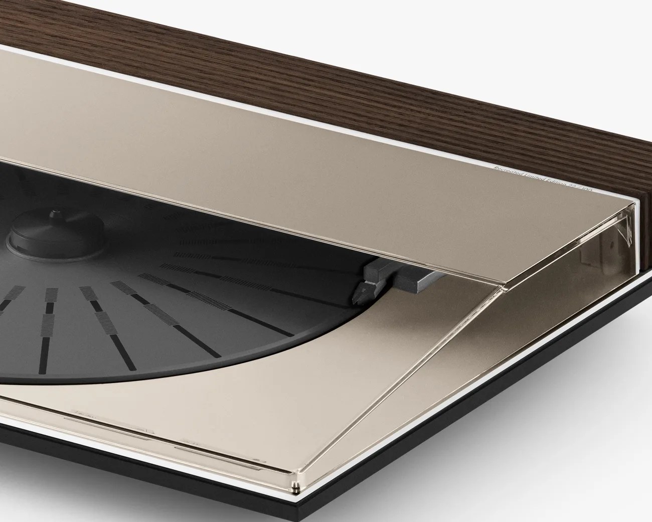 Close-up of a modern turntable with a transparent dust cover, black platter, and wood grain accent.