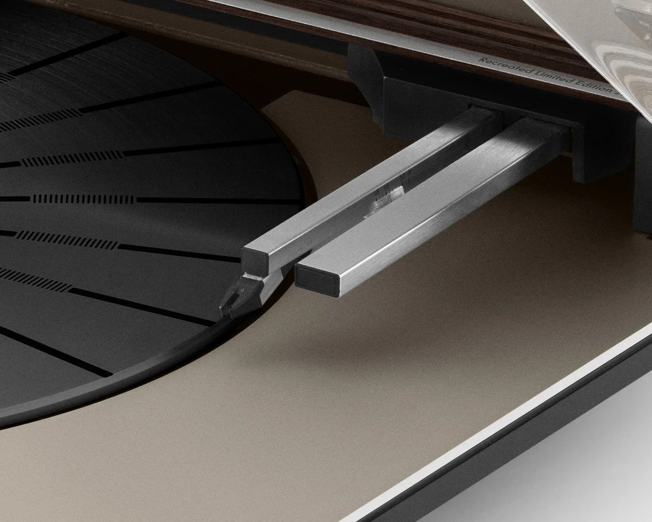 Close-up of a turntable tonearm with a stylus on a black platter with radial grooves.