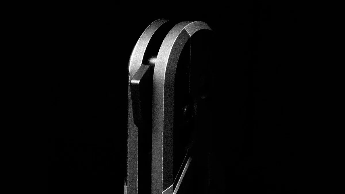 Close-up of a metallic object with two parallel curved edges and a rectangular protrusion, set against a black background.