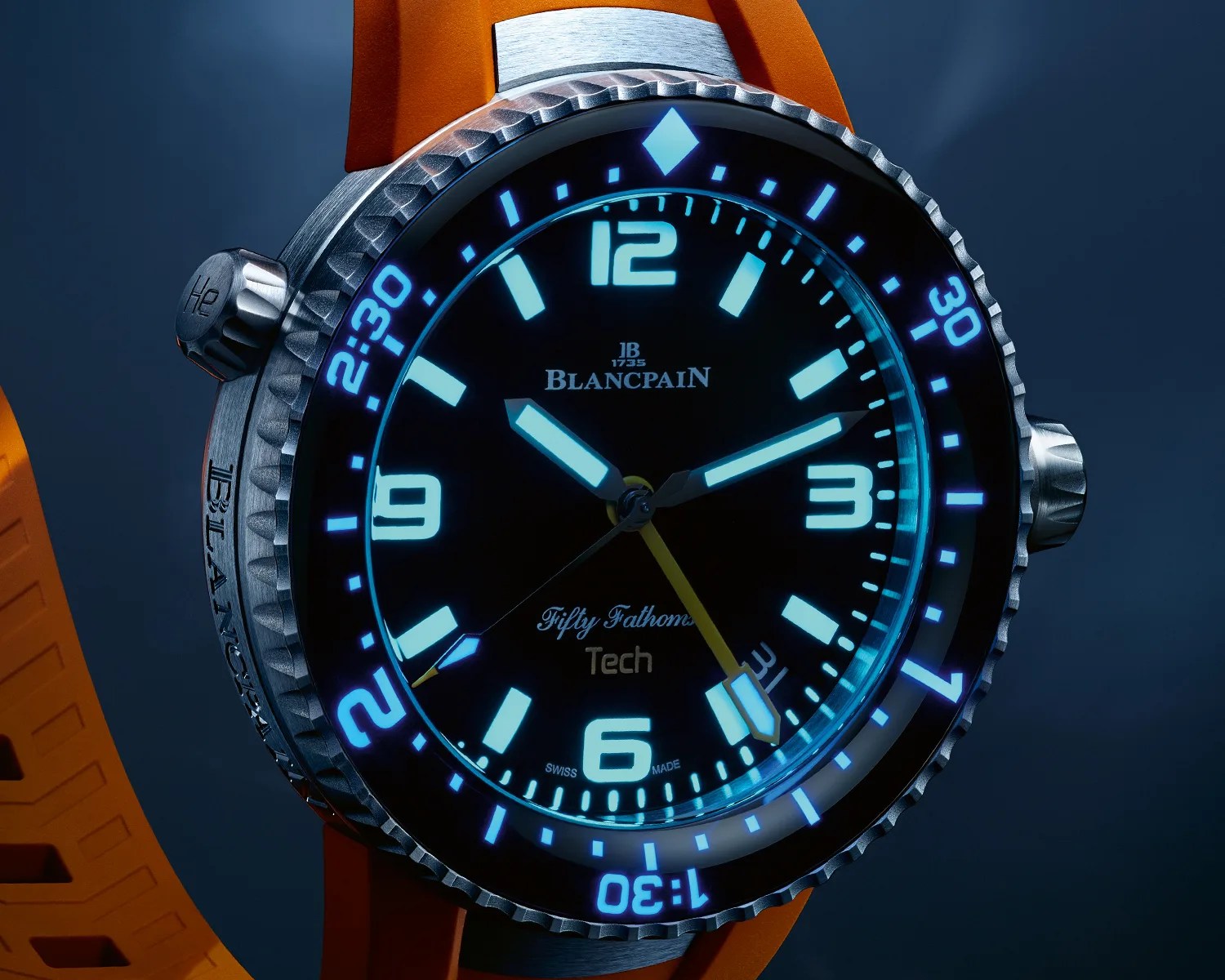 Close-up of a Blancpain Fifty Fathoms Tech dive watch with glowing blue markers and an orange strap.