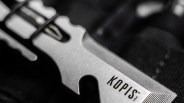 Close-up of a silver metal zipper pull with the brand name "KOPIS" engraved on it.