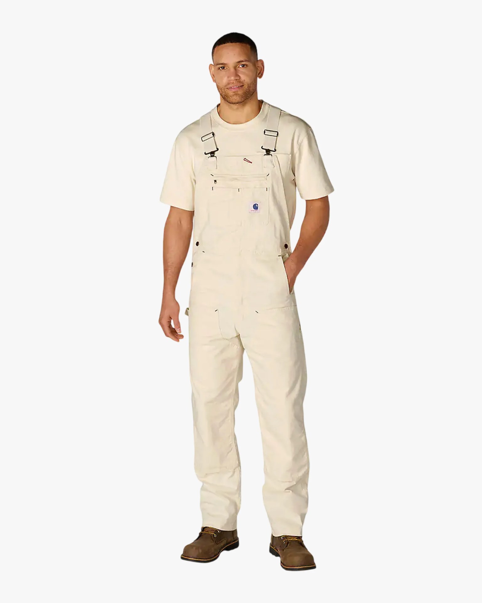 Man wearing cream-colored Carhartt overalls with a front pocket and brown work boots.