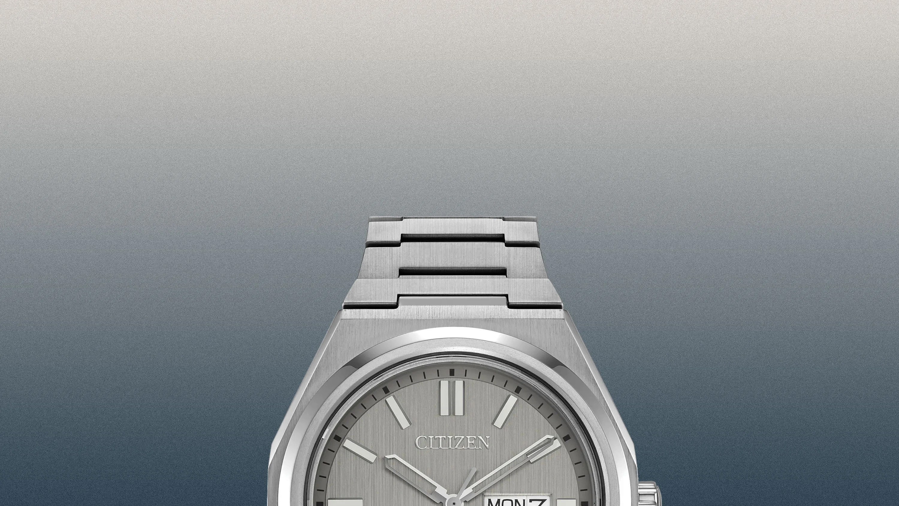 Close-up of a silver Citizen wristwatch with a metal link band and day-date display on a gradient gray background.