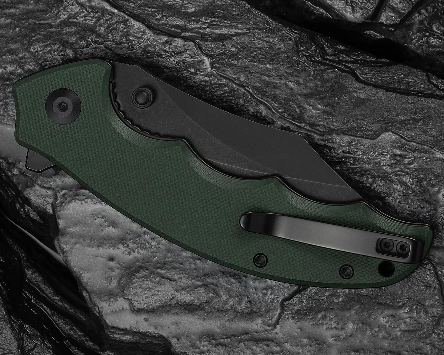 Folded black blade pocket knife with textured dark green handle and black clip on a textured dark stone surface.