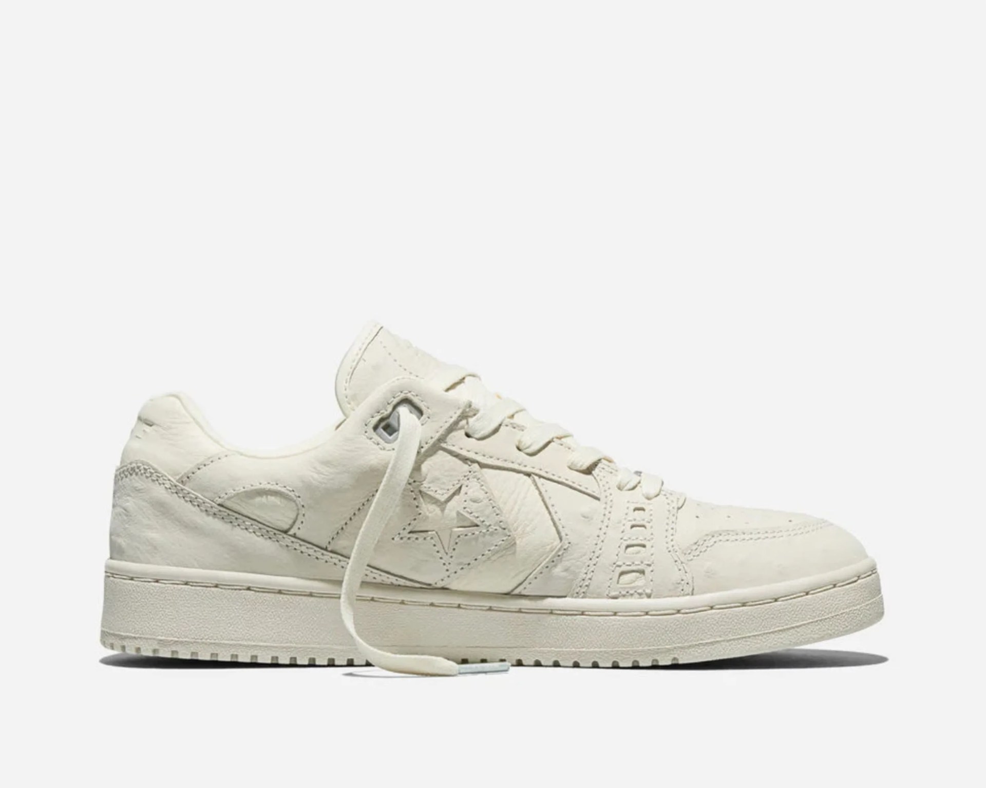Off-white leather low-top sneaker with star logo and thick sole.