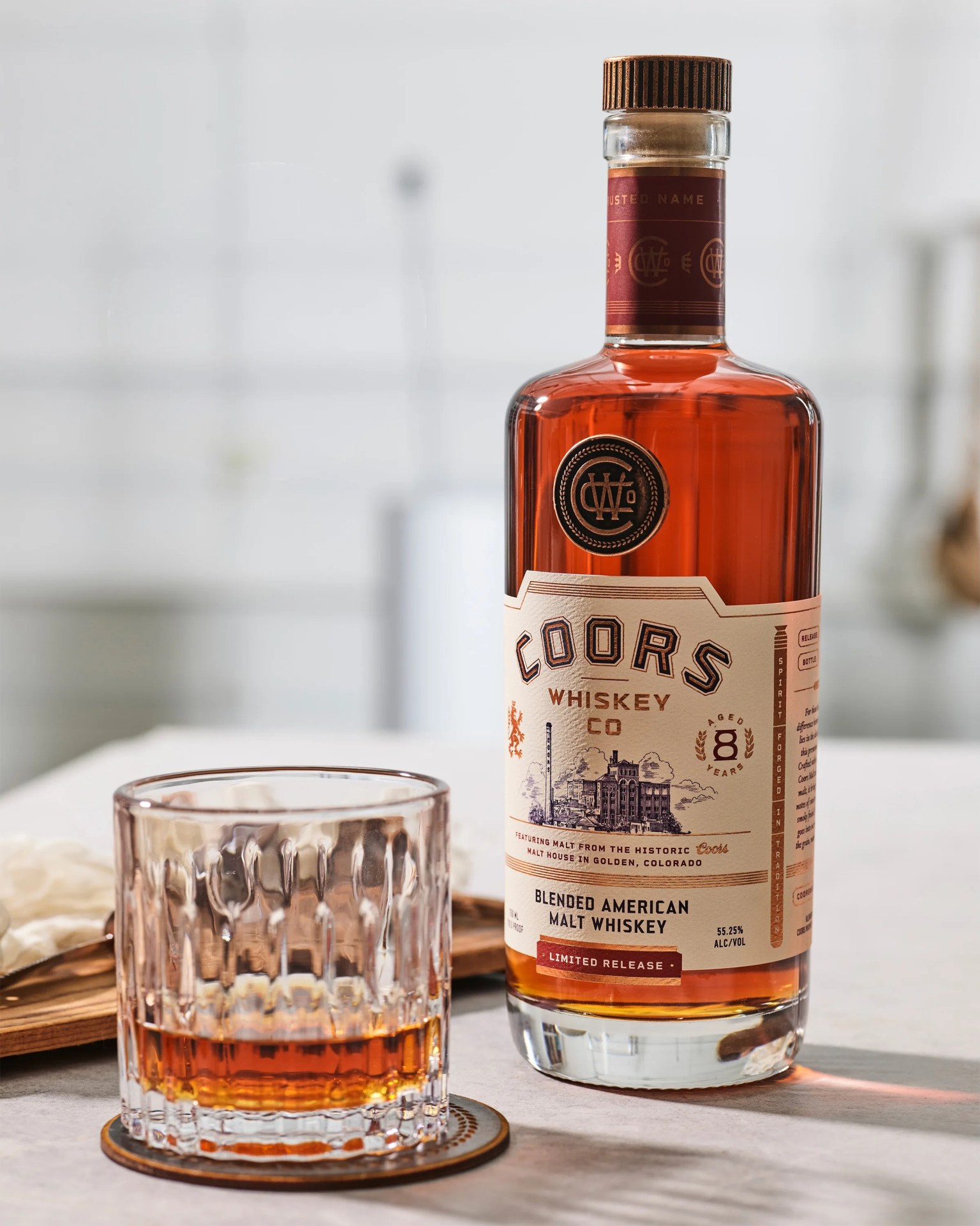 Bottle of Coors Whiskey Co blended American malt whiskey with a glass of whiskey on a coaster.