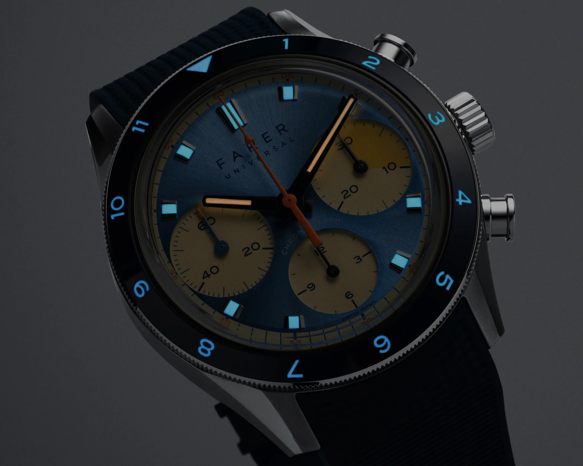 Close-up of a Farer Universal chronograph watch with a blue dial, beige subdials, black bezel with blue numerals, and black strap.