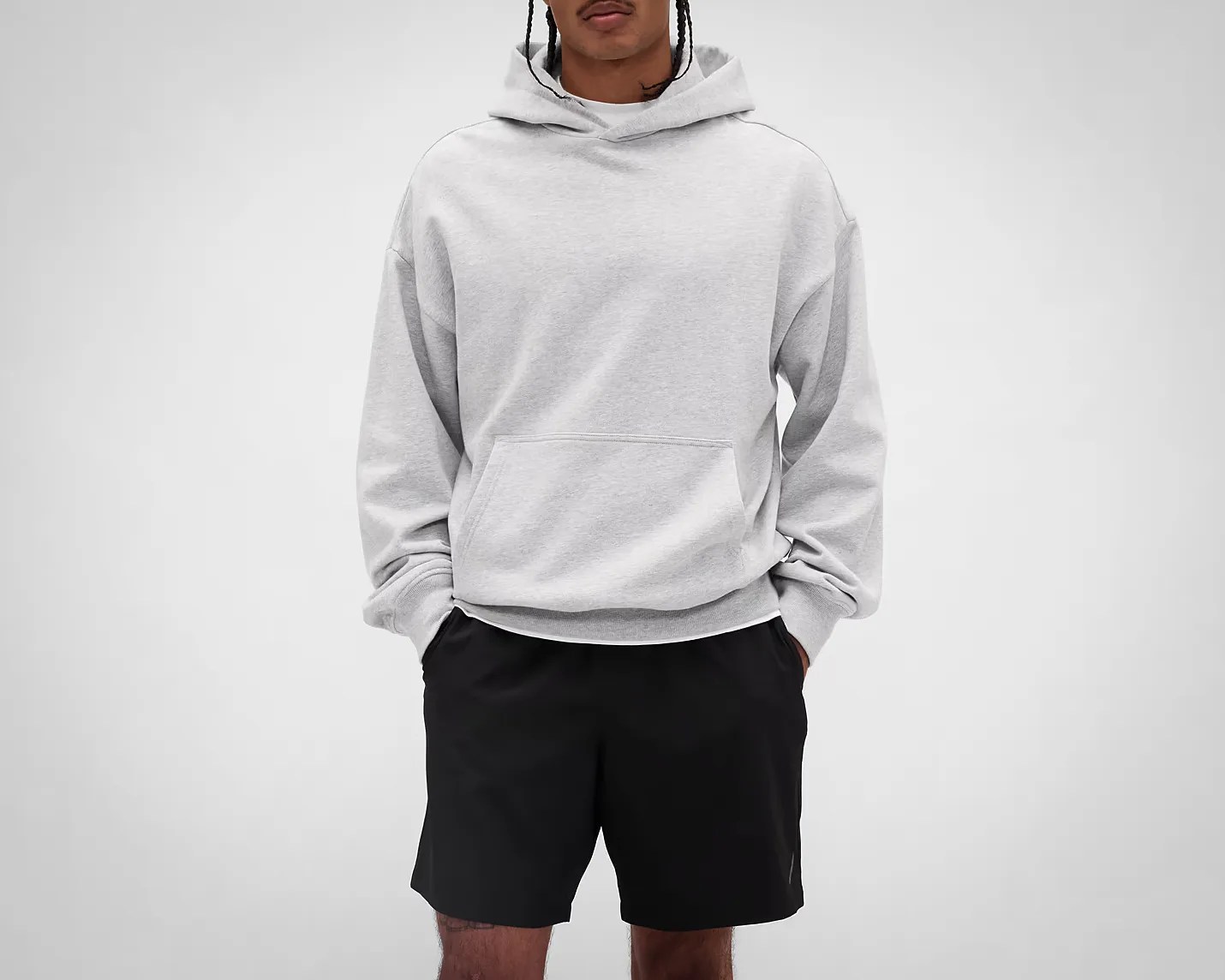 Light gray pullover hoodie with kangaroo pocket worn with black shorts.