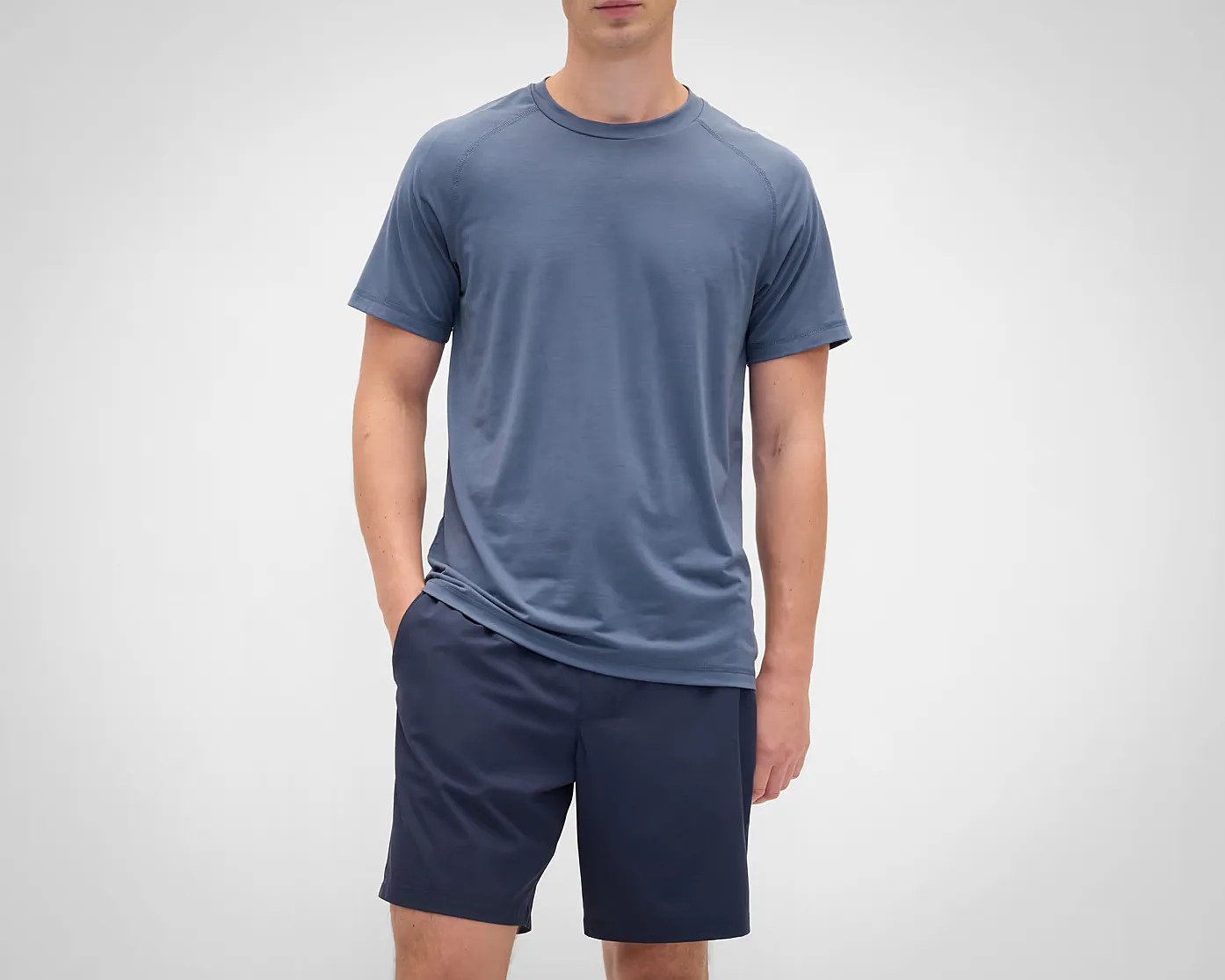 Blue short-sleeve crew neck t-shirt worn with navy shorts on a person against a plain background.