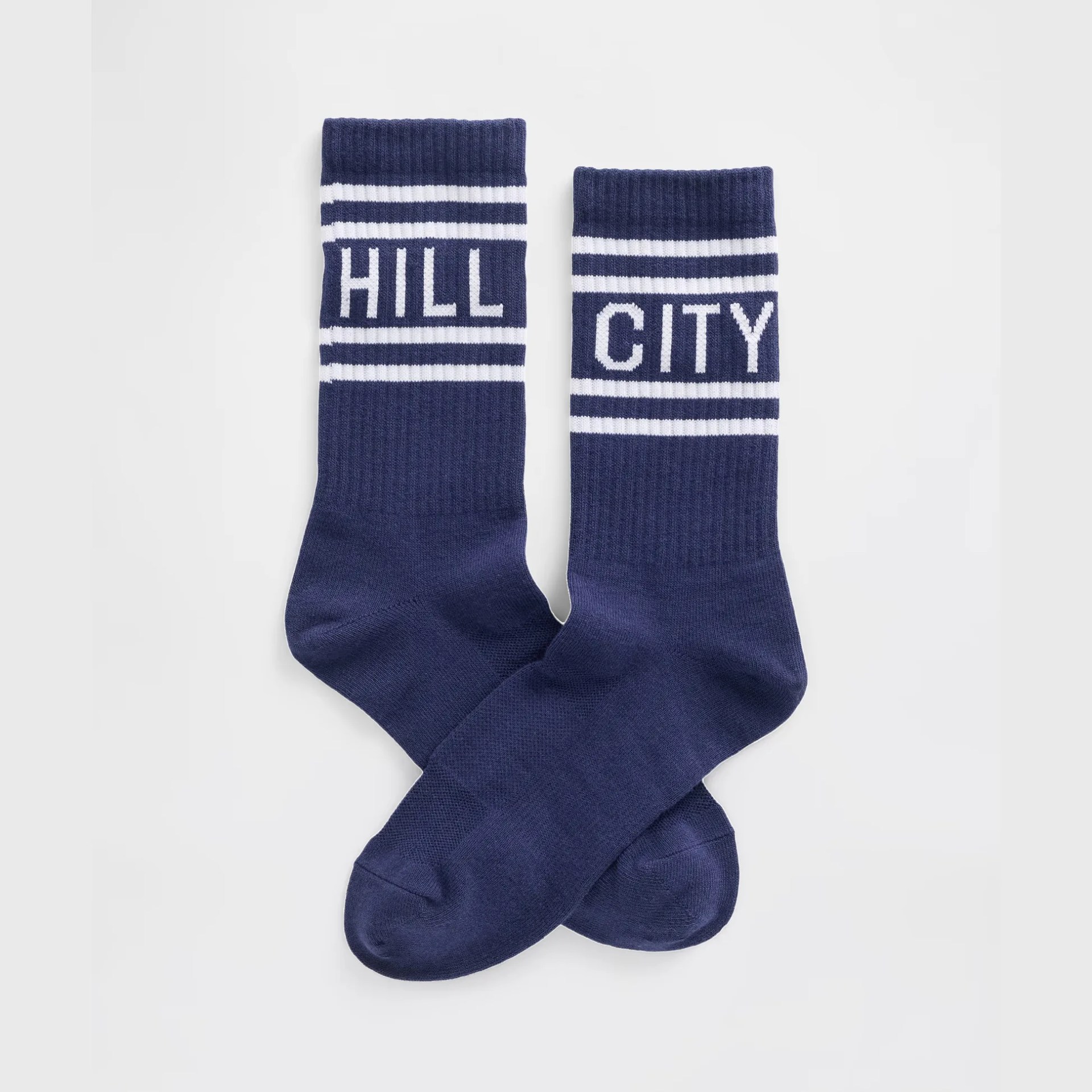 Pair of navy blue socks with white stripes and the words "HILL" and "CITY" knitted near the top.
