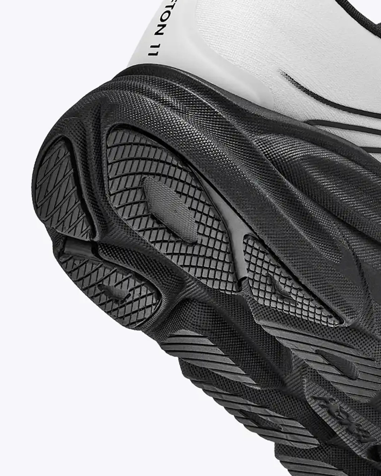 Close-up of a black textured rubber outsole with a white upper part of a sneaker.