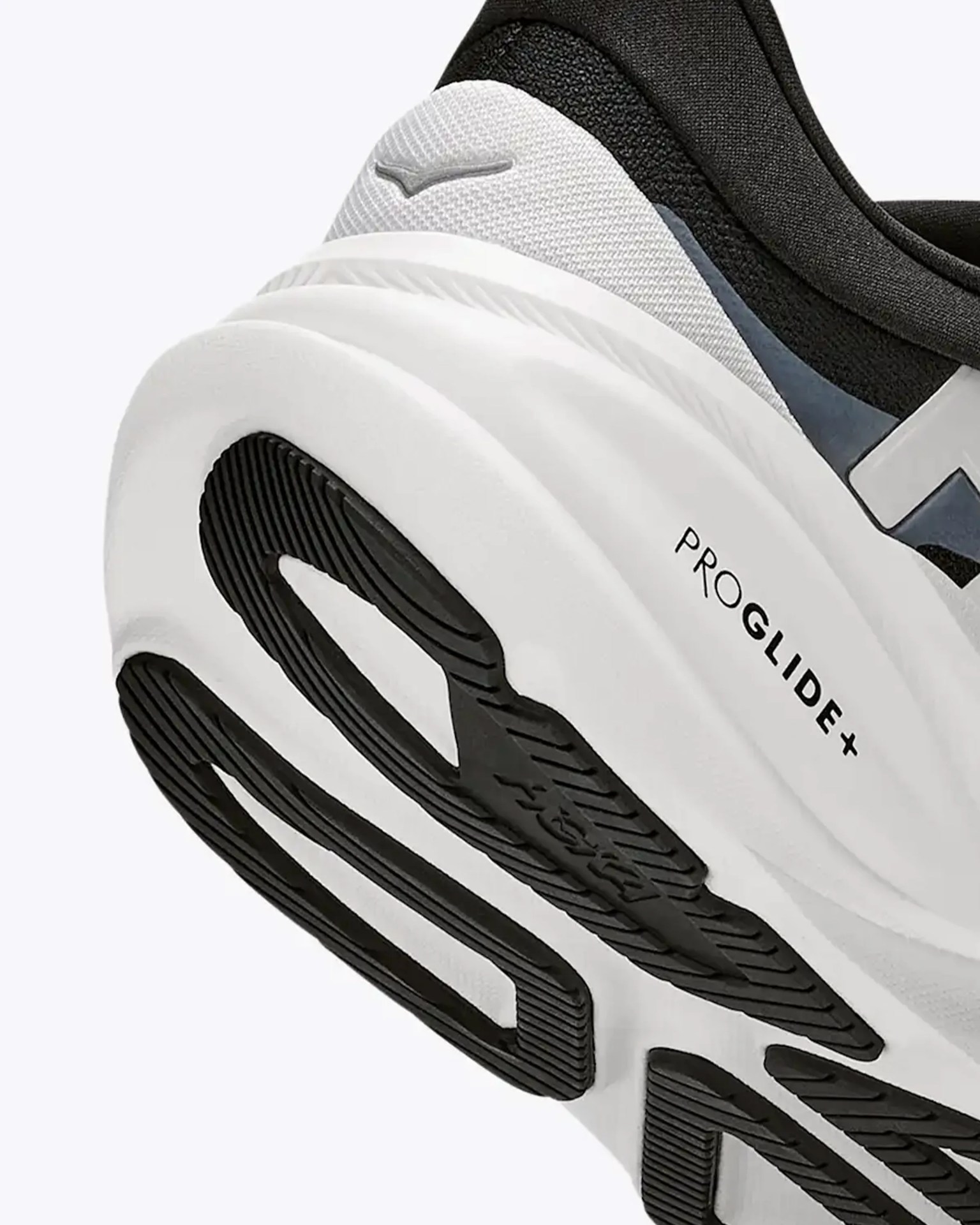 Close-up of a white and black sneaker sole with "PROGLIDE+" text and textured black rubber tread.