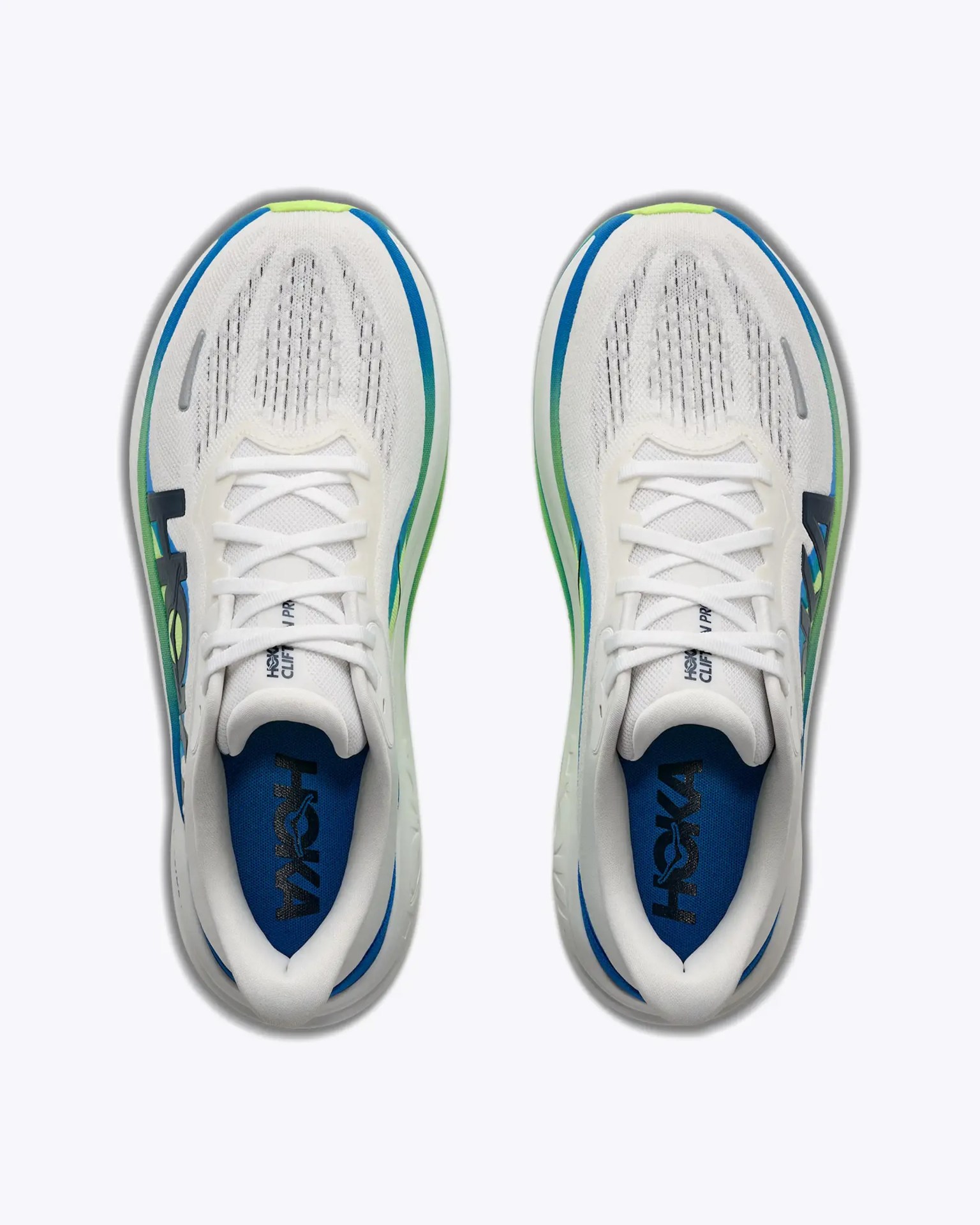 Top view of white Hoka running shoes with blue and green accents and blue insoles.