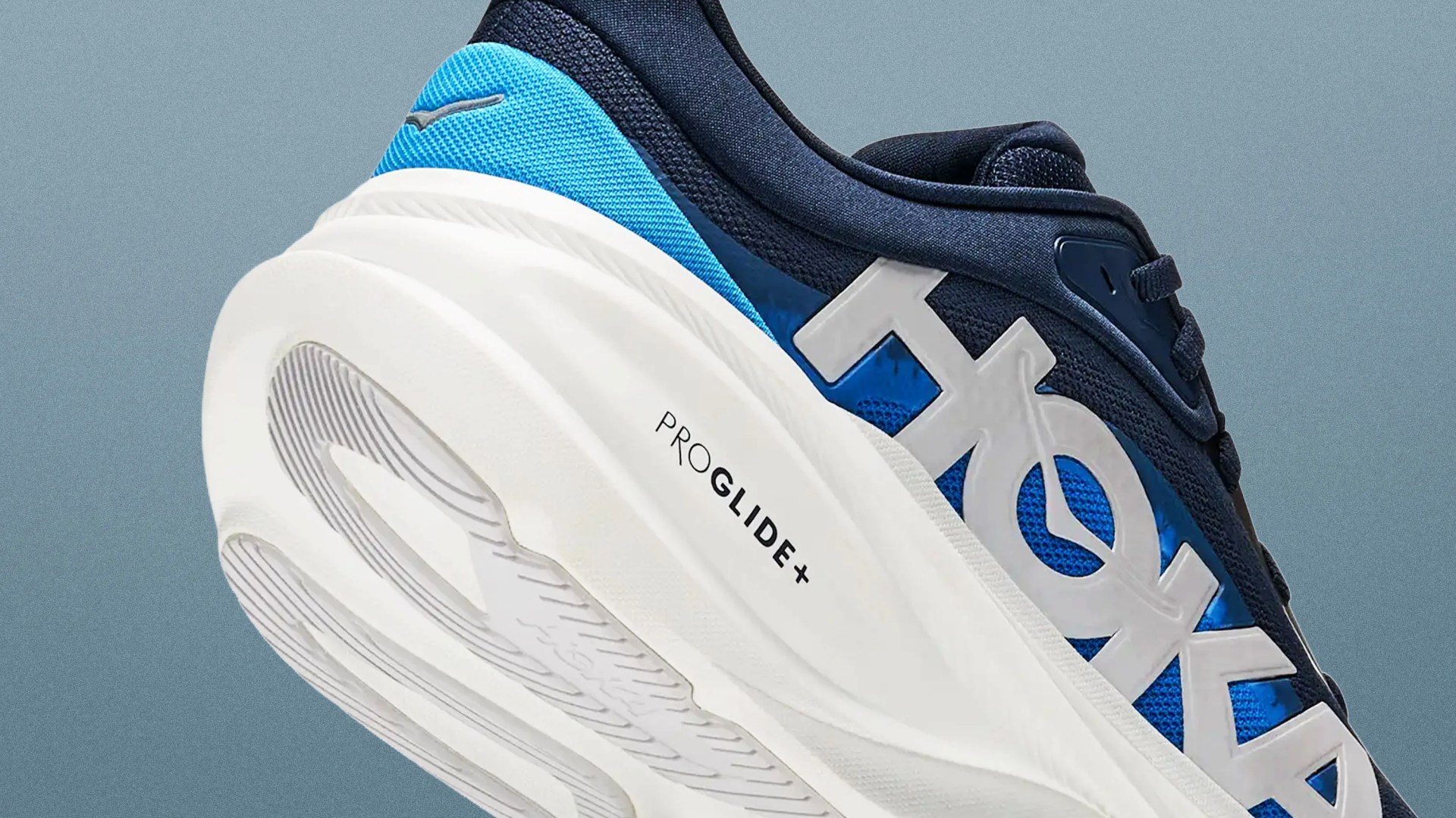 Close-up of a blue and navy sneaker with white sole featuring "PROGLIDE+" text and large white logo on the side.