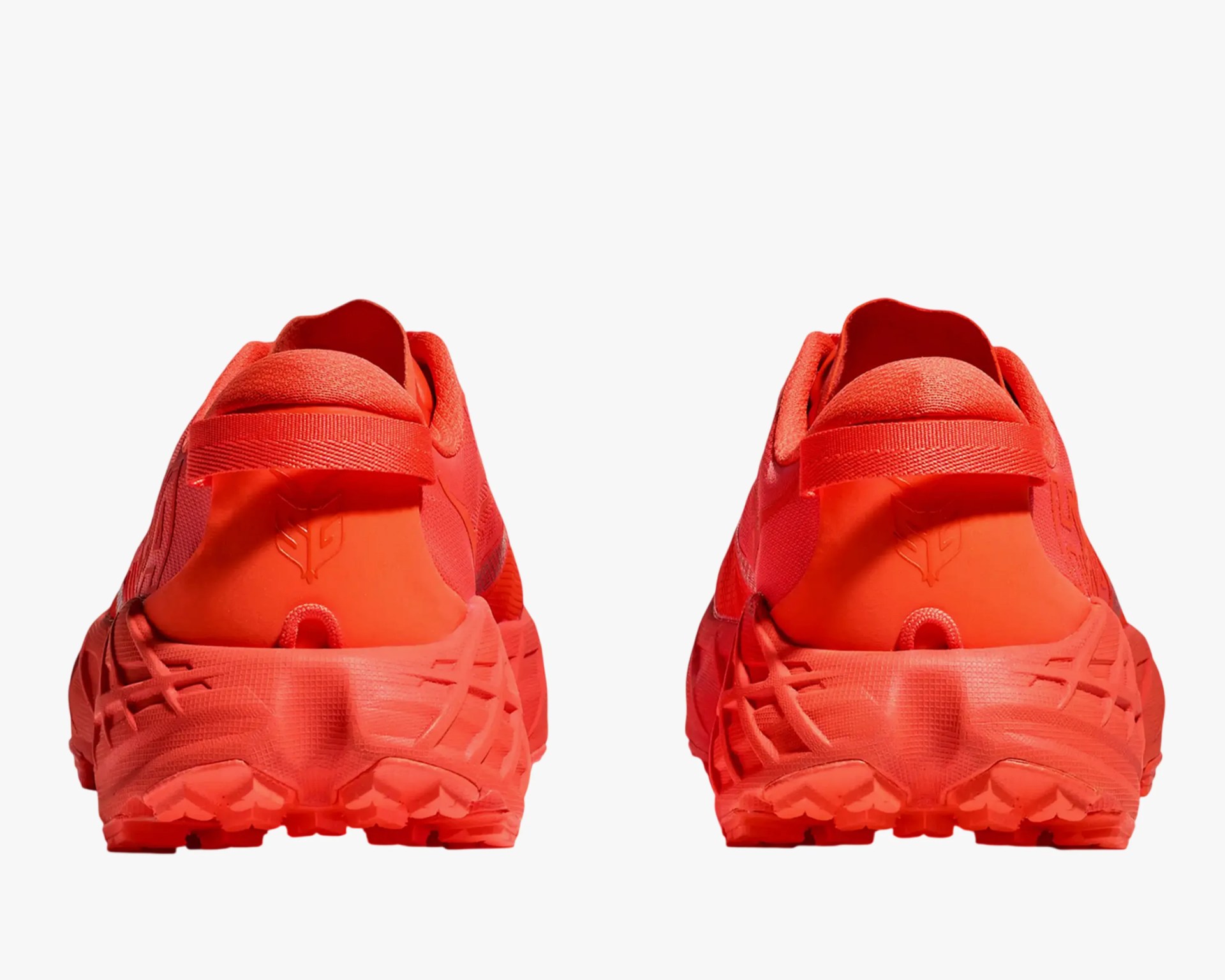 Pair of bright red athletic shoes viewed from the back, showing textured soles and heel loops.