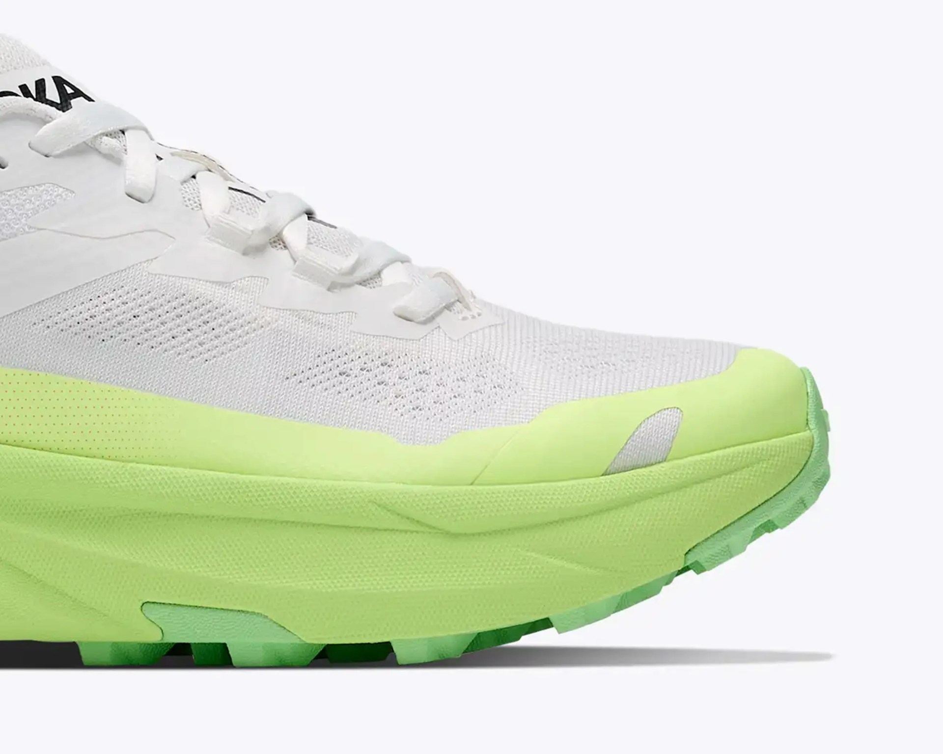 White and light green running shoe with mesh upper and thick sole.