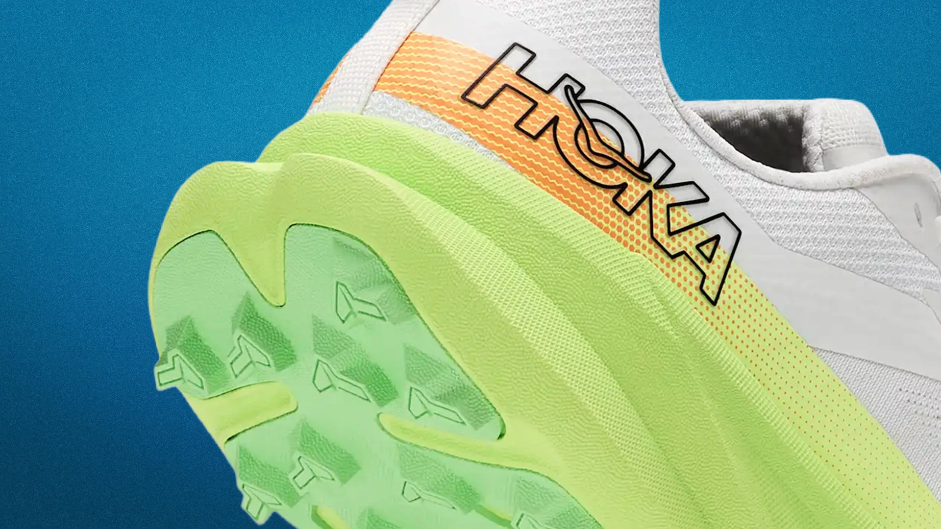 Close-up of a white HOKA sneaker with a green sole and orange-yellow gradient detail on the side.