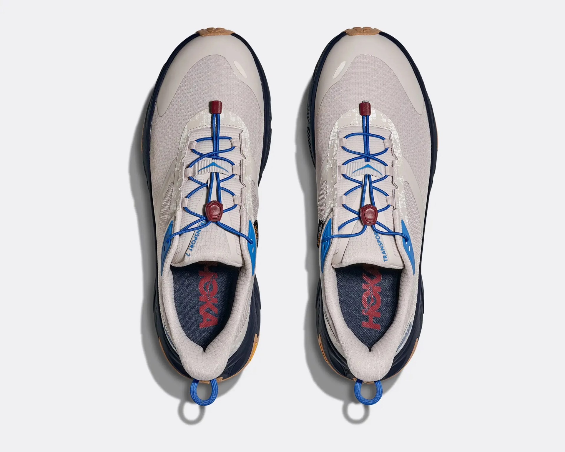 Pair of beige and navy sneakers with blue elastic laces and red lace locks, viewed from above.