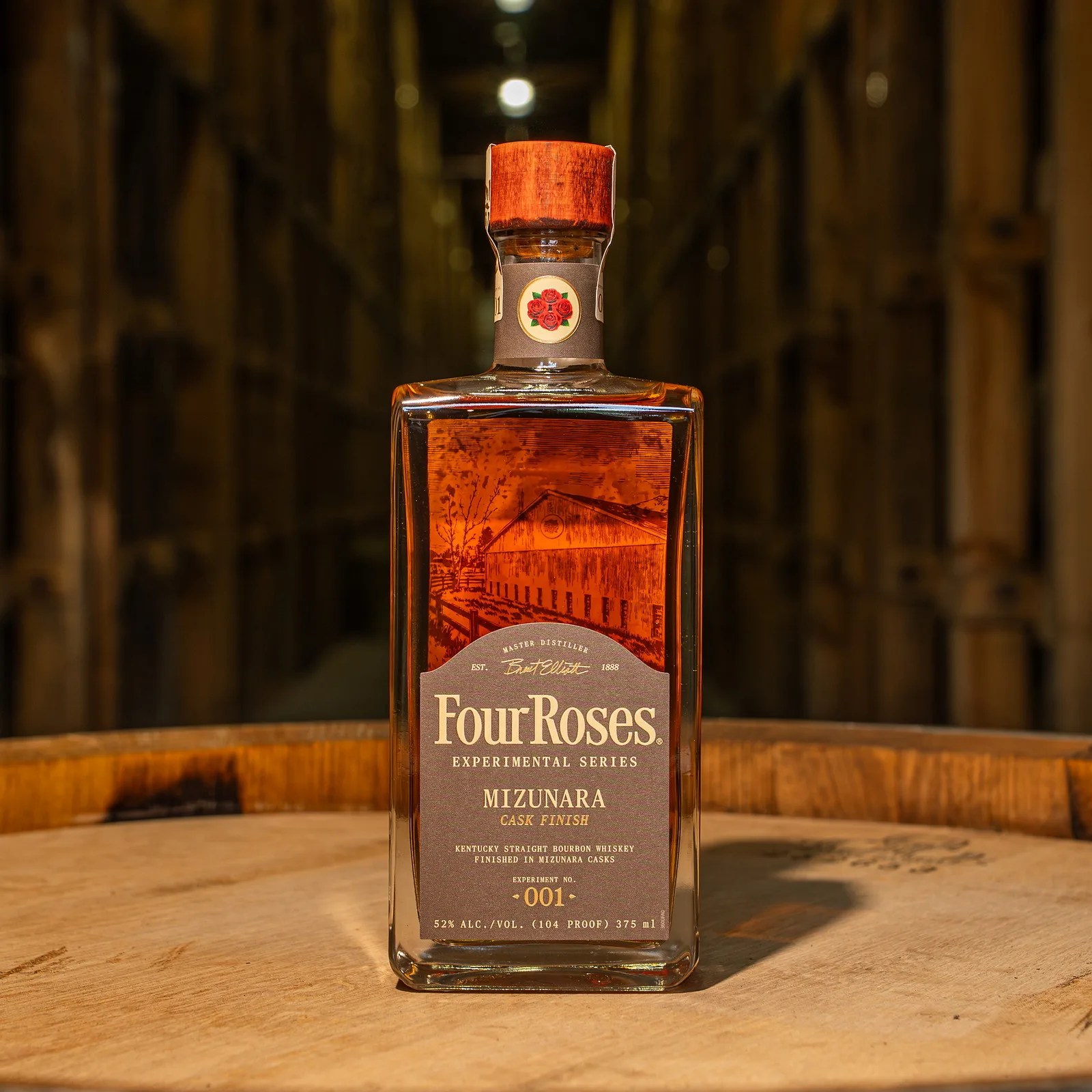 Square glass bottle of Four Roses Experimental Series Mizunara Cask Finish bourbon whiskey on a wooden barrel.