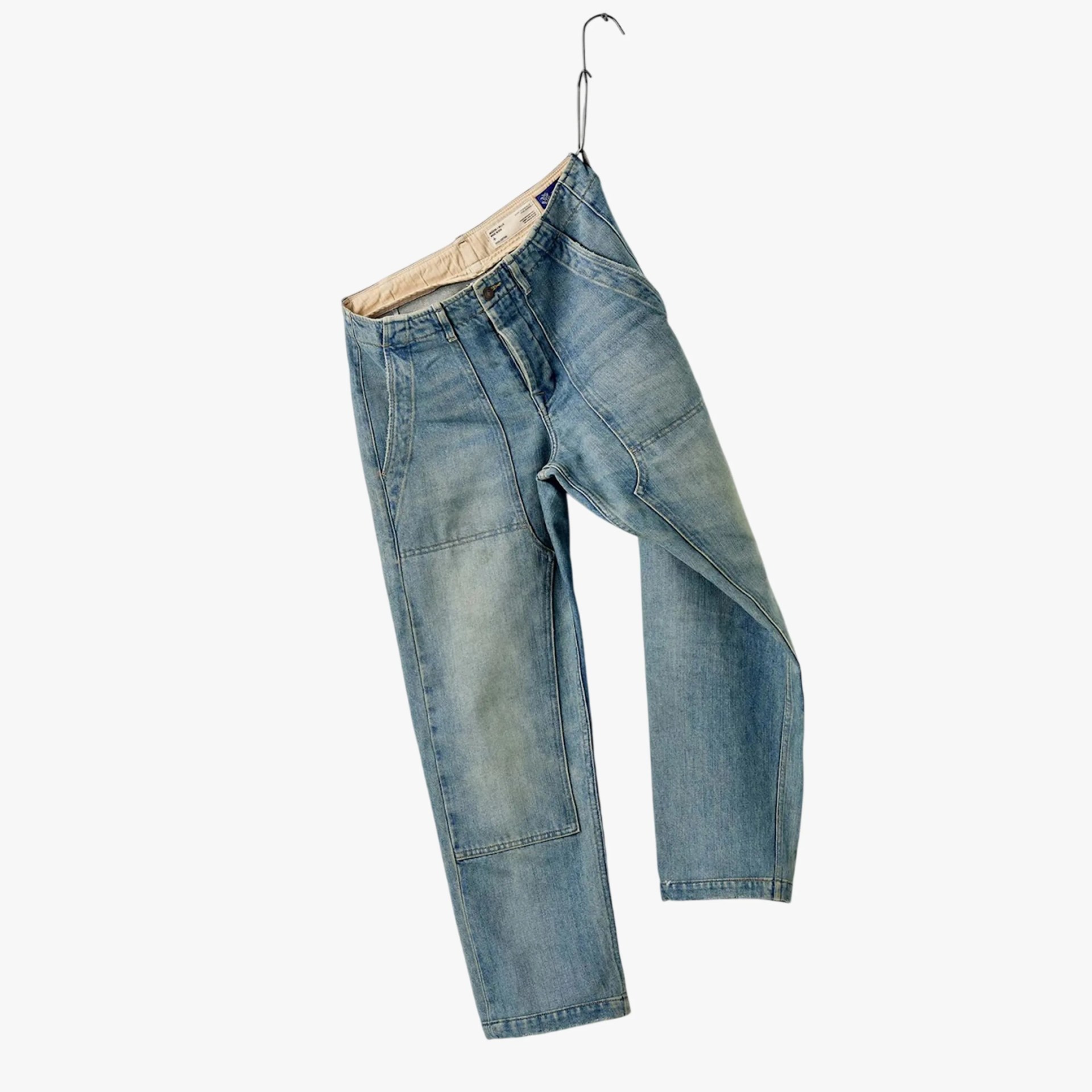 Light blue denim jeans with patch details hanging on a metal hanger against a white background.