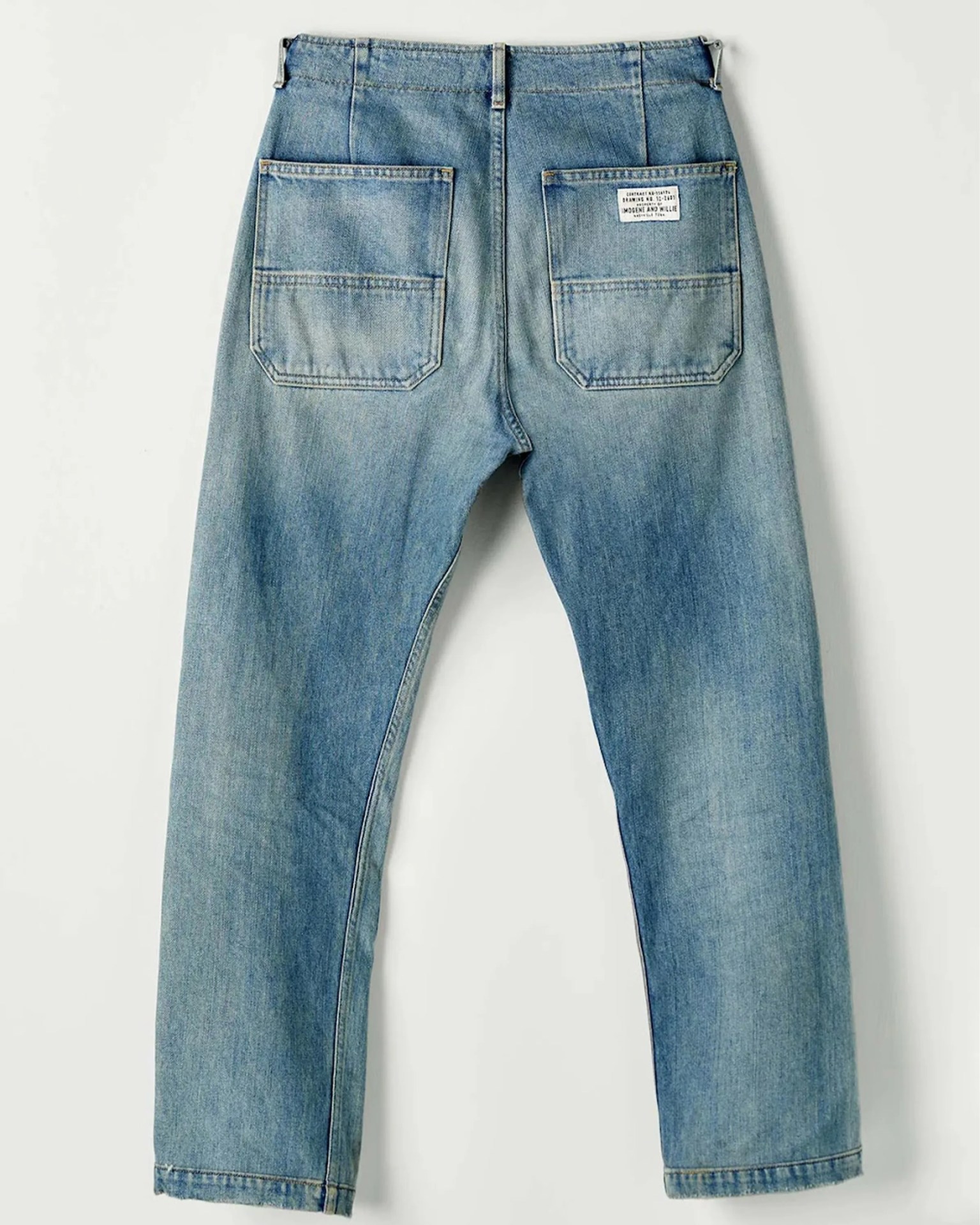 Light blue denim jeans with two large back pockets, one featuring a white label patch.