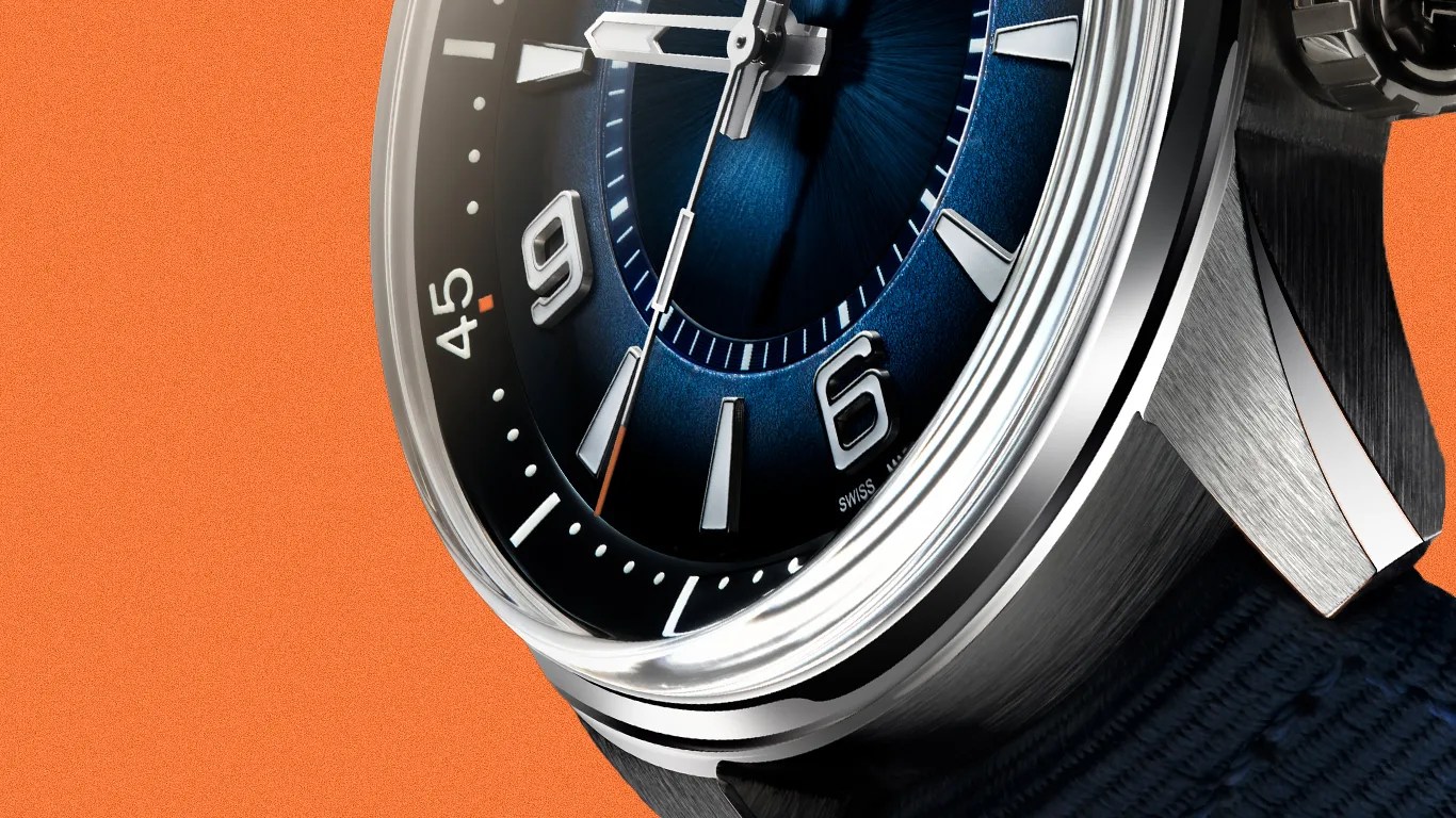 Close-up of a stainless steel watch with a blue sunburst dial, silver hour markers, and a navy fabric strap on an orange background.