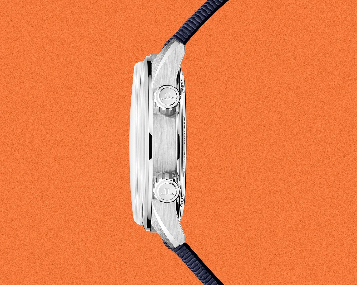Side view of a silver stainless steel watch case with two crowns and a navy blue fabric strap on an orange background.