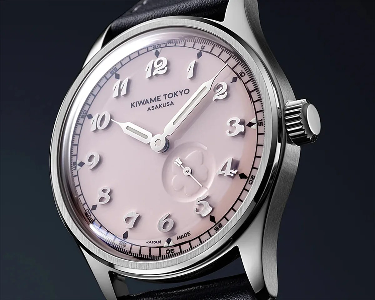 Silver stainless steel wristwatch with a pale pink dial, raised white numerals, and black leather strap.