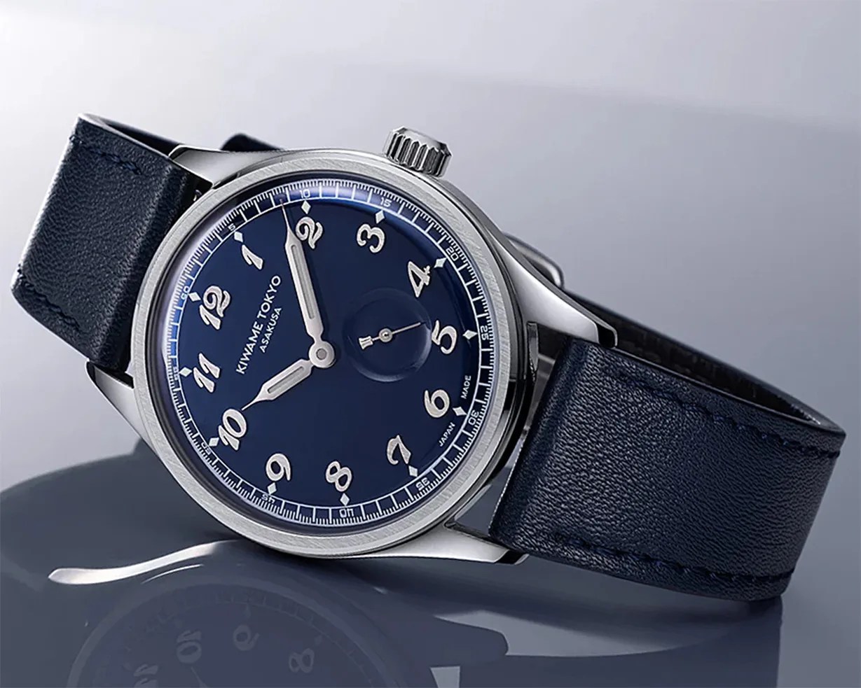 Silver wristwatch with a navy blue dial, white numerals, and a matching navy leather strap.