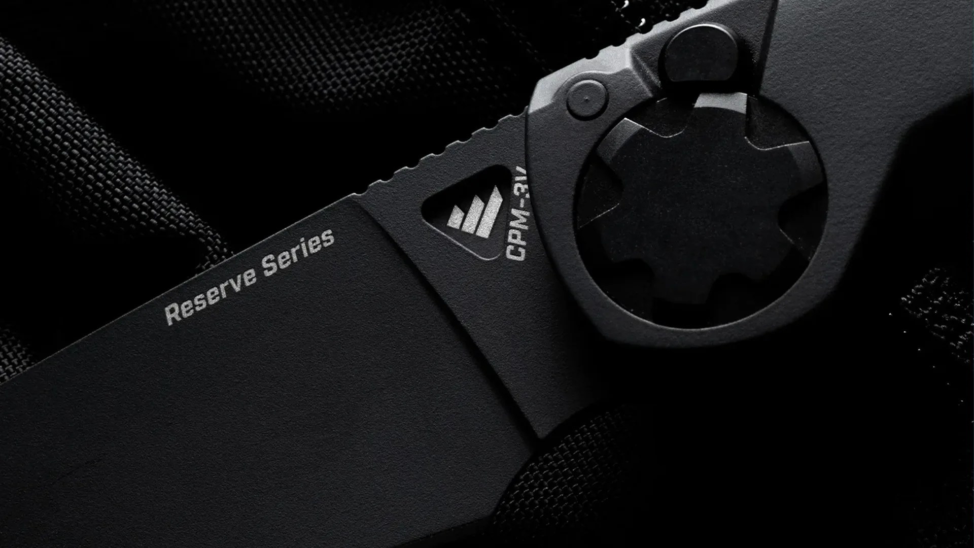 Close-up of a black folding knife blade with "Reserve Series" and "CPM-3V" markings near the pivot.
