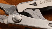 Close-up of a stainless steel multitool with pliers and a partially visible "LEATHER" engraving on the handle.