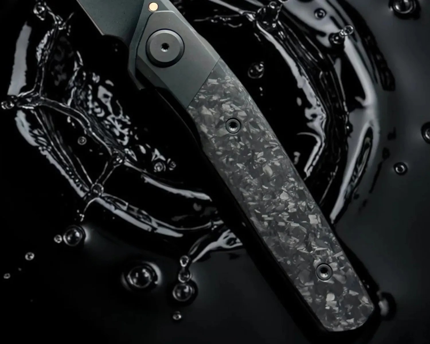 Close-up of a black folding knife handle with a textured, marbled pattern submerged in dark liquid.