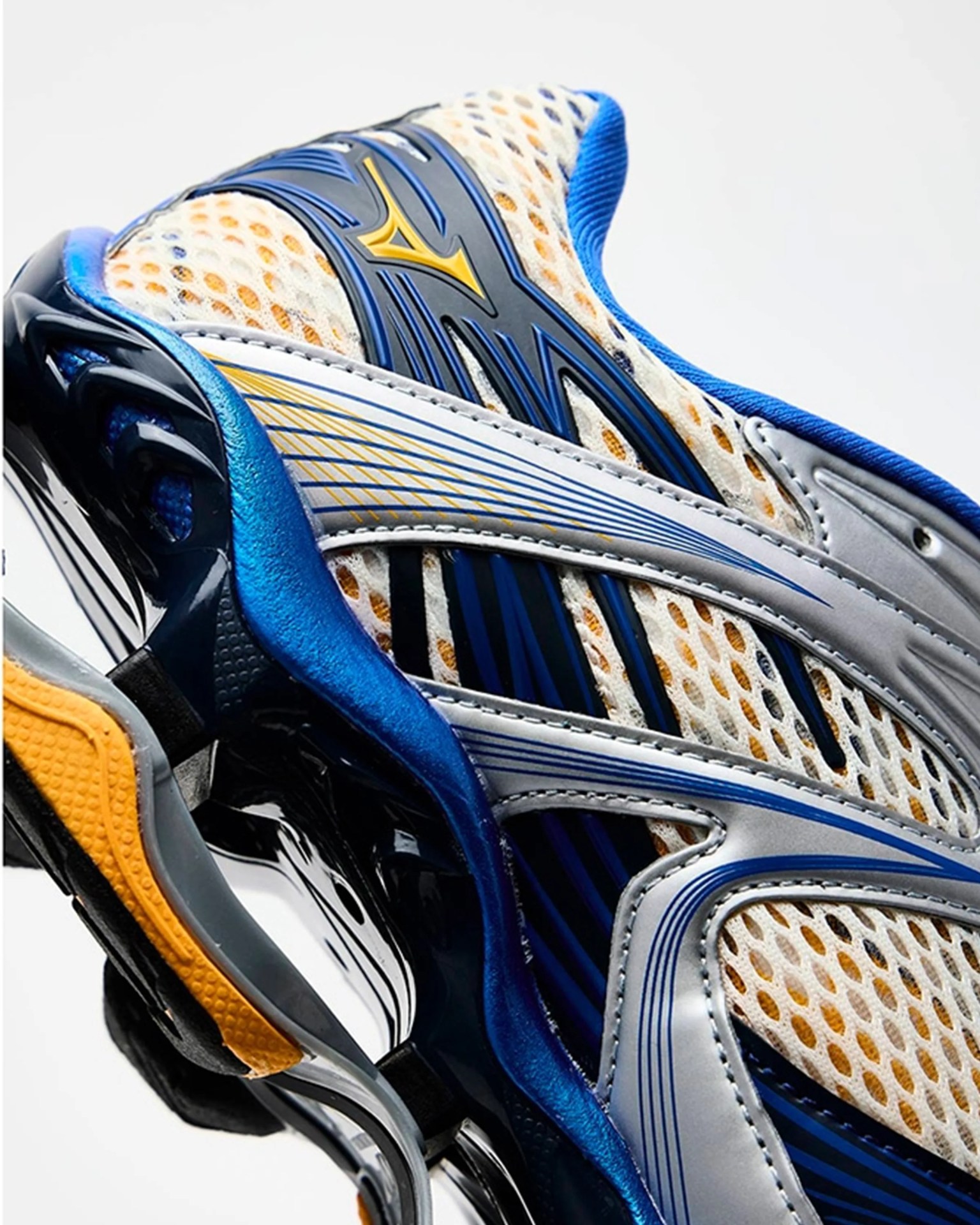 Close-up of a blue, white, and yellow Mizuno running shoe with mesh upper and intricate sole design.