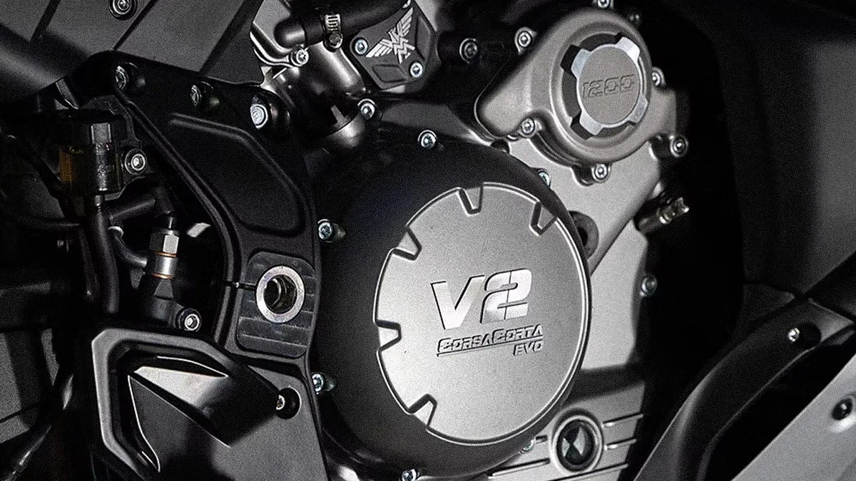 Close-up of a motorcycle engine cover with "V2 CORSA CORTA EVO" embossed on the metallic surface.