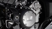 Close-up of a motorcycle engine cover with "V2 CORSA CORTA EVO" embossed on the metallic surface.