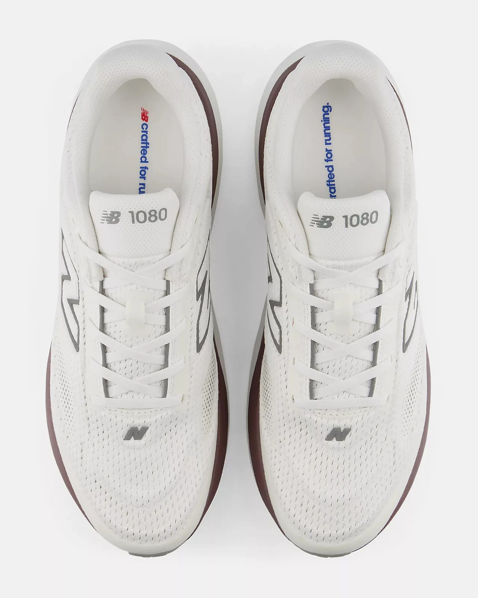 Pair of white New Balance 1080 running shoes with gray logos and maroon midsoles, viewed from above.