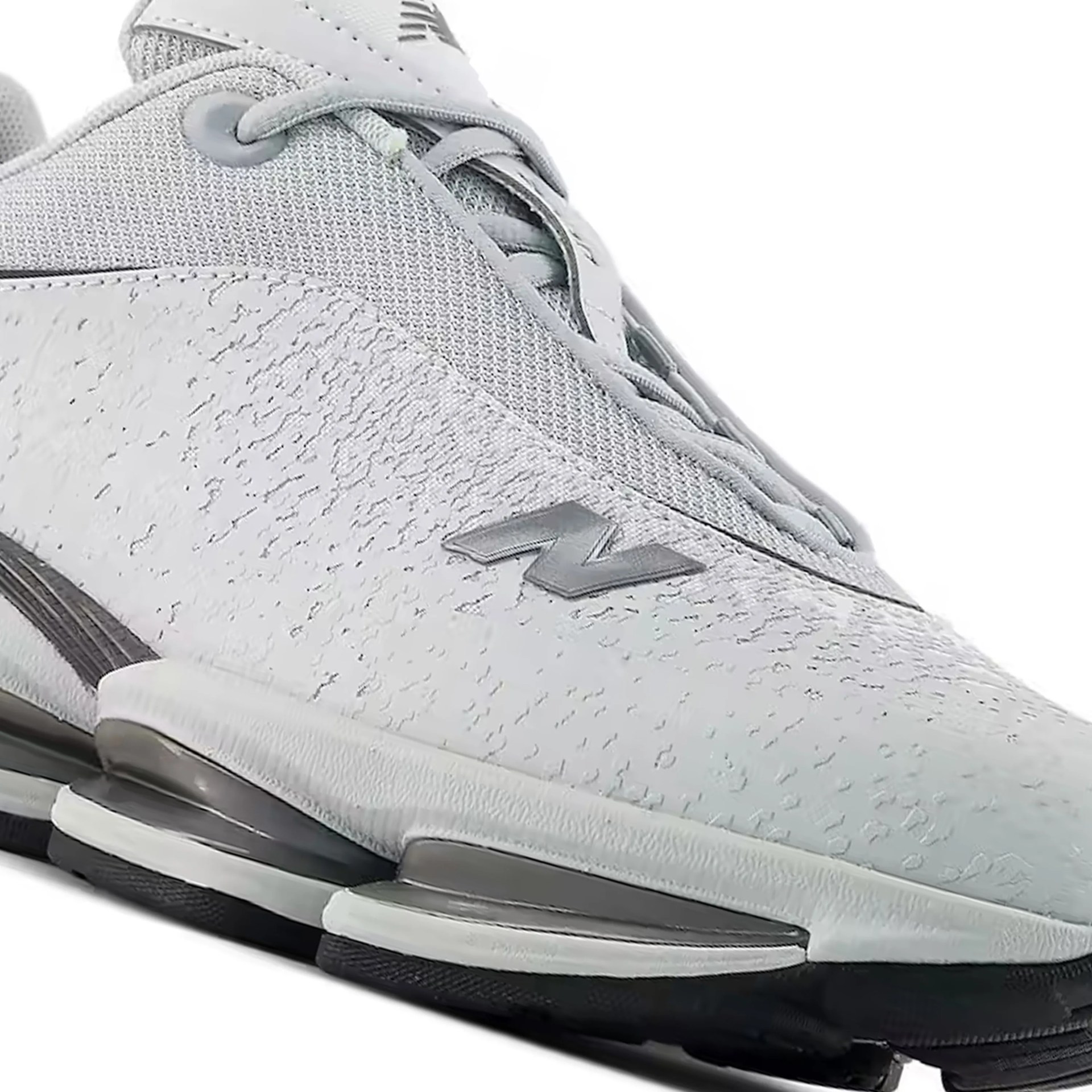 Light gray New Balance sneaker with textured upper and segmented sole with black and white accents.