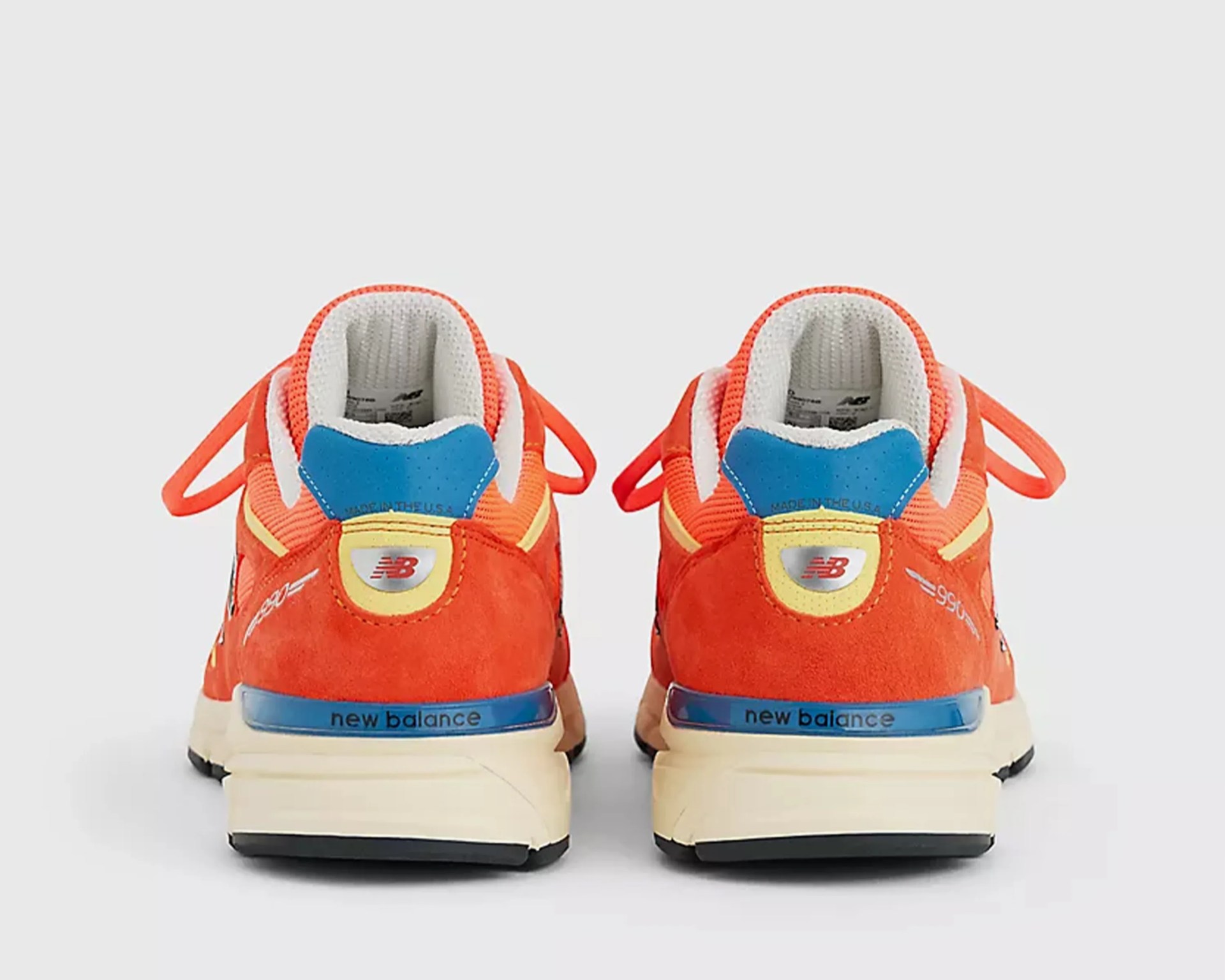 Pair of orange New Balance sneakers with blue and yellow accents viewed from the back.